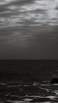 A serene black and white  of the ocean's waves and shore