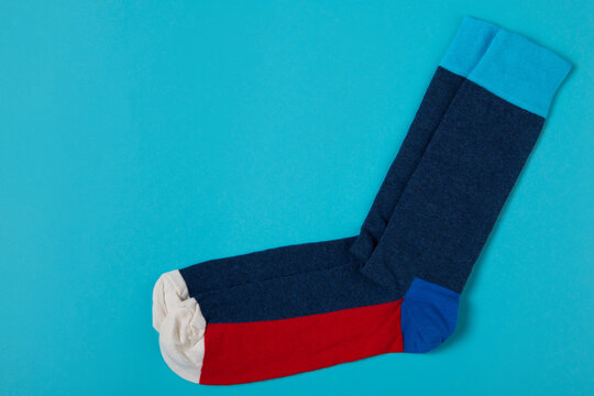 Pair of color block socks on blue background with copy space. Modern colorful knit socks flat lay top view