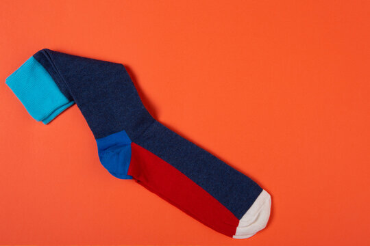 Pair of color block socks on bright orange background with copy space. Modern colorful knit socks flat lay top view