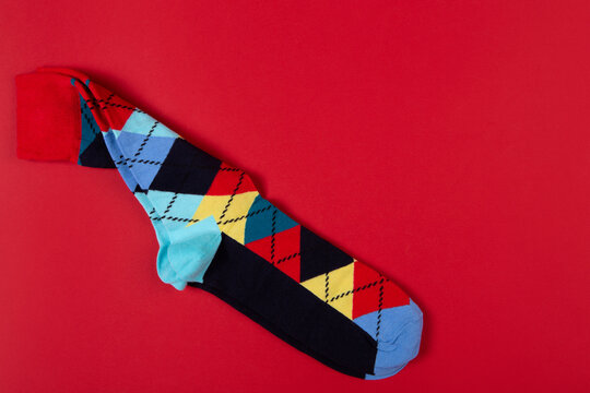 Pair of colorful argyle socks on bright red background with copy space. Classic diamond pattern knit socks flat lay top view