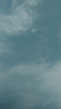 A small  through a cloudy blue sky with white puffy clouds