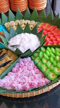 Vertical pan shot of traditional Indonesian snacks platter Jajanan Pasar decorated on banana leaf