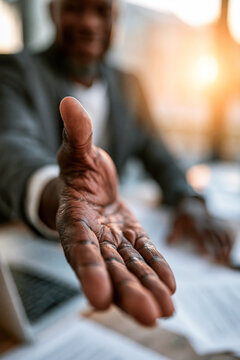 A first person perspective of a business handshake offer with shallow depth of field.