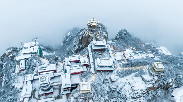 Snow-covered Golden Summit temples on Laojun Mountain in Henan, China, surrounded by dramatic winter mountain scenery.