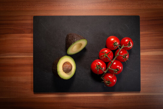 Halved Avocado and Vine Tomatoes on Cutting Board