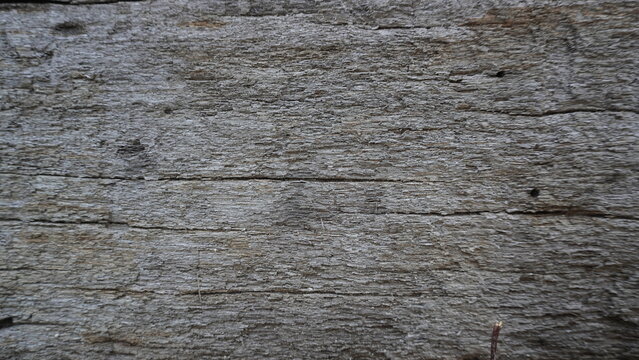 Full frame view of a weathered grey wood surface with deep horizontal grain lines.