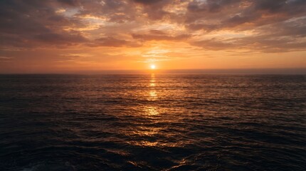 Fototapeta premium A stunning golden sunset over the calm ocean horizon with soft clouds and light reflecting on the water surface