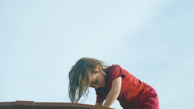 Young boy climbing a metal dome climber at the playground seen from below against the sky