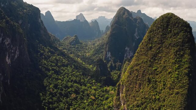 KHAO SOK National Park in Thailand stunning aerial views of towering limestone karst mountains covered with lush tropical rainforest and vibrant jungle vegetation under cloudy sky. Aerial view flight