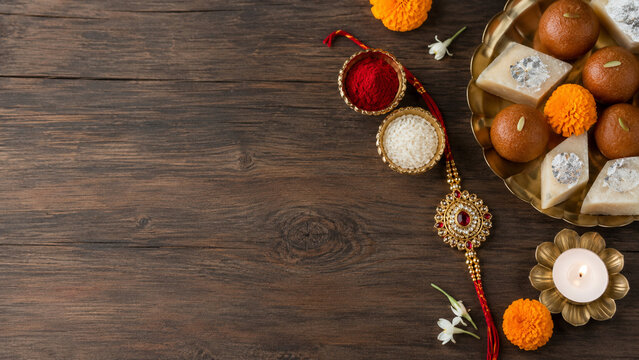 Raksha Bandhan background with Rakhi and Indian sweets on wood