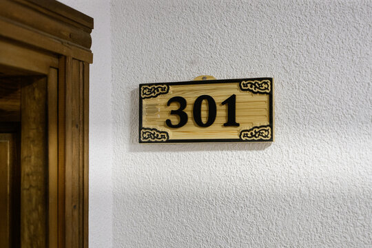 Wooden hotel room number 301 plate on wall, vintage apartment door sign close up, boutique guest house accommodation, hospitality concept. Concept of hospitality, room booking, apartment finding.