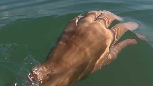 Woman touching seawater with hand. 4k