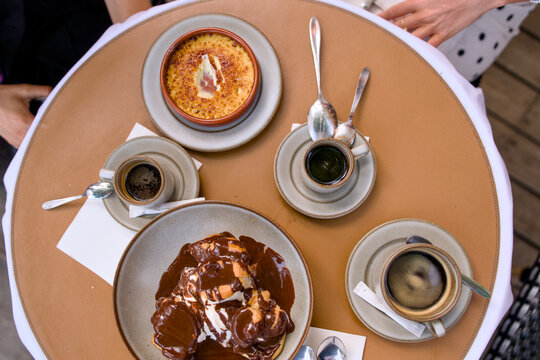 Overhead view of dessert and coffee service at Parisian cafe table