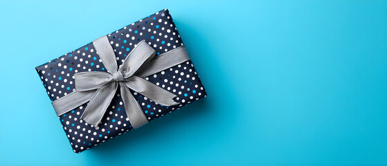 Obraz premium Top view flat lay of blue polka dot wrapped gift box tied with striped ribbon bow isolated on bright cyan background holiday birthday celebration concept