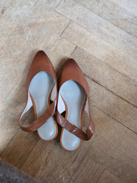 vintage brown female shoes are placed on a wooden floor in a room
