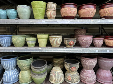 Different types and sizes of pots on metal shelves in a garden store