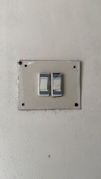 Two worn out light switches on a dirty beige wall