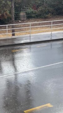 Rainy urban road in a Mediterranean setting, filmed during a heavy rain shower. Rainy day atmosphere and wet road reflections