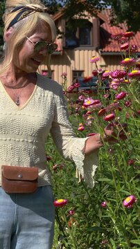 Woman walking in a beautiful blooming flower garden. Vertical design in 9:16 ratio. Smartphone and social media ready.	