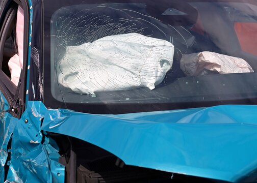 Cracked windscreen, with an airbag inside the car, after a road collision. Front view, close up.