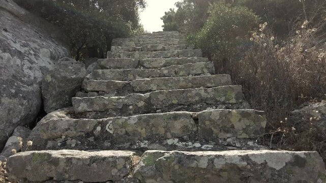 4k, footage stepping up stairs of ancient granite slabs amongst mediterranean shrubs, vegetation, Sardinia, Gallura, tourism, traveling, trekking, outdoors, hiking