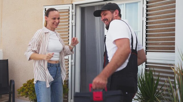 Joyful homeowner and handyman celebrating a successful repair project together, dancing and giving high five at the front door, illustrating positive teamwork, trust and excellent customer service.