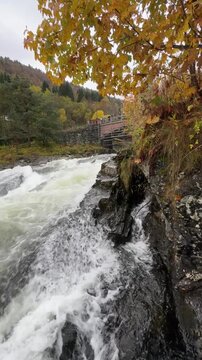 HELLESYLT, NORWAY - OCTOBER 9, 2024: View of the famous Hellesylt waterfall flowing through the village, with the bridge and surrounding buildings in the Norwegian fjords.