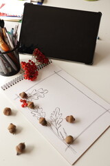 Autumn composition for studyind. Tablet with blank screen. On the table is paper with a frame for text. Rowan berries and acorns on the table.  © Olga_Burtseva