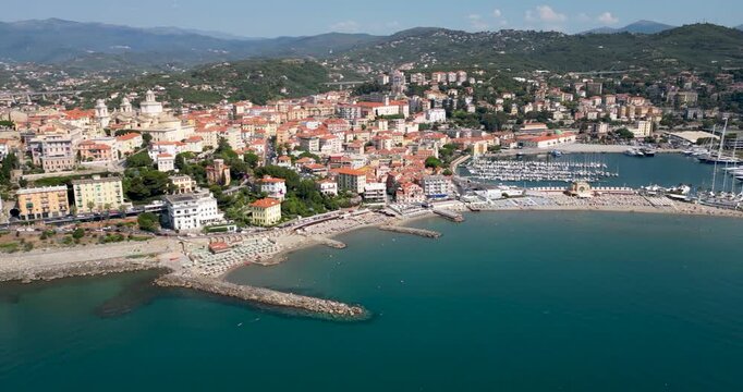 Aerial drone view of Imperia city harbour and beach with yachts docked in marina colourful buildings and surrounding hills on a sunny day in Liguria Italy