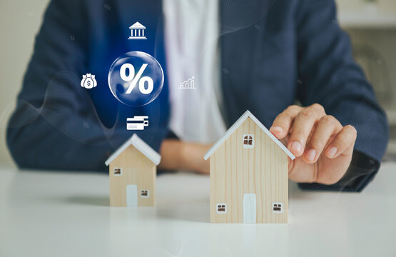 Mortgage financing concept with businessperson holding model house to represent interest rates home loans banking property investment affordability financial planning and real estate.