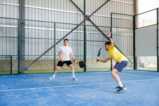 Padel doubles players compete during indoor tournament match