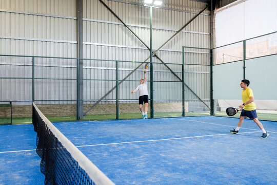 Padel doubles player return ball during indoor tournament match