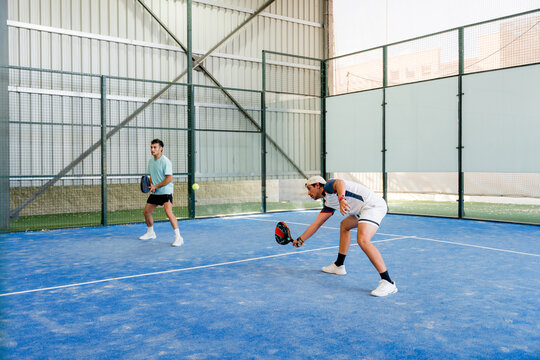 Padel player return ball during indoor tournament match