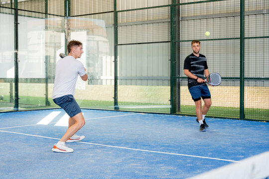 Padel doubles match with two male players on indoor court