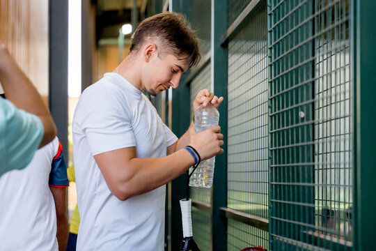 Padel player hydrate with water bottle beside court