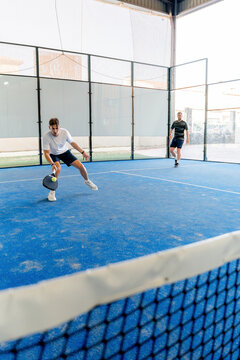 Padel player return ball during indoor doubles tournament
