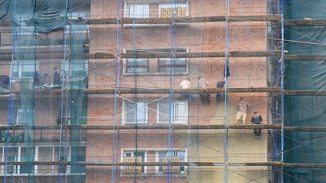 Construction workers standing on scaffolding in front of a building