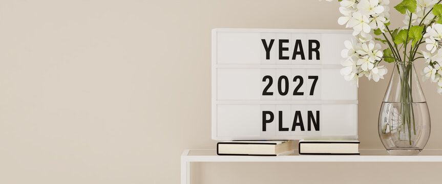 A lightbox displaying the words "Year 2027 Plan" on a shelf with books and plants. Copy space, web banner format.