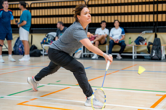 Woman compete in indoor badminton tournament match
