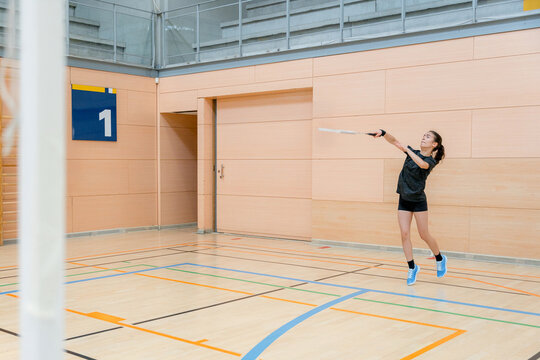 Woman competing in an indoor badminton tournament match