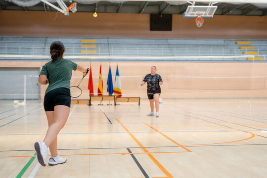 Women compete in badminton tournament at indoor court