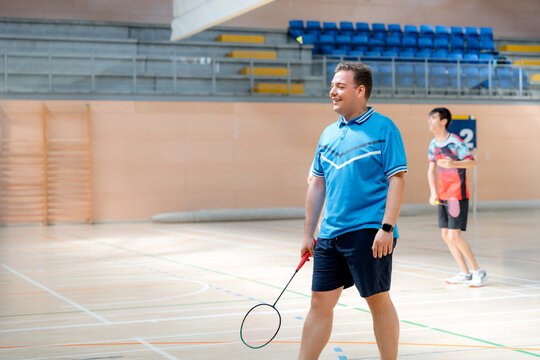 Smiling badminton player with racket at indoor tournament
