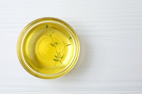 Bowl of thyme oil on white background
