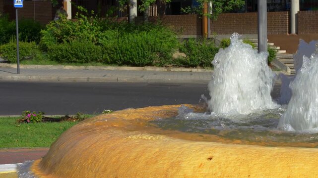 Slow motion pigeon standing beside flowing water on a yellow city fountain in sunlight