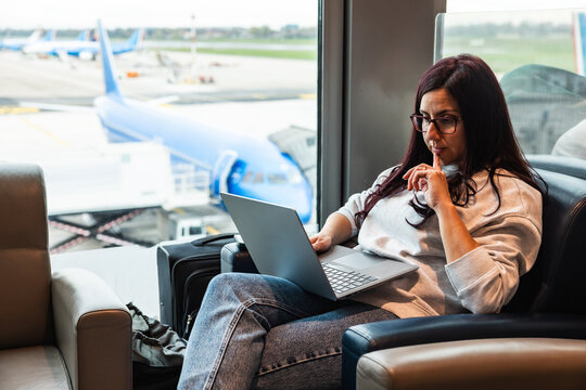 Woman working on laptop in airport lounge