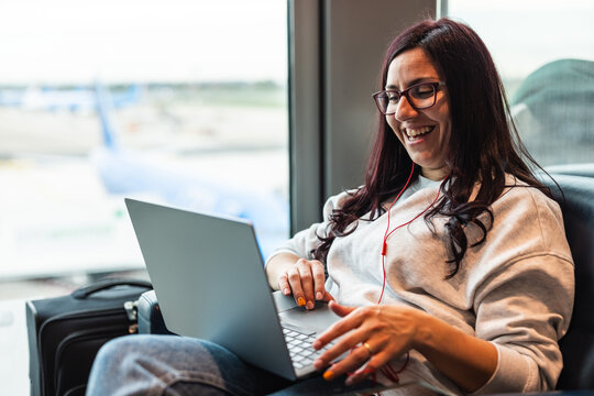 Happy woman at airport using laptop