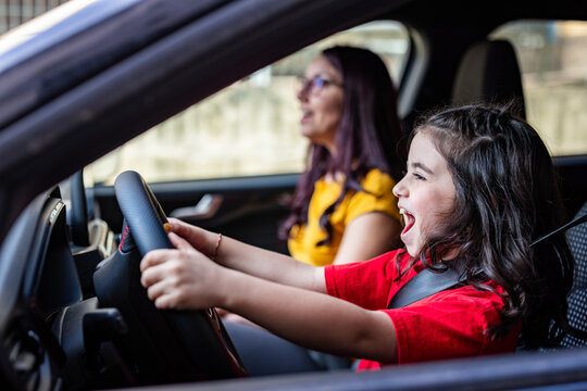 Little girl playing driving car with mother