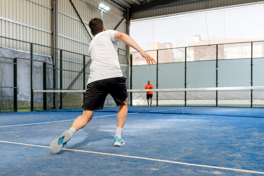 Padel doubles match on indoor court with male player