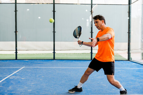 Padel player return ball during doubles match on indoor court