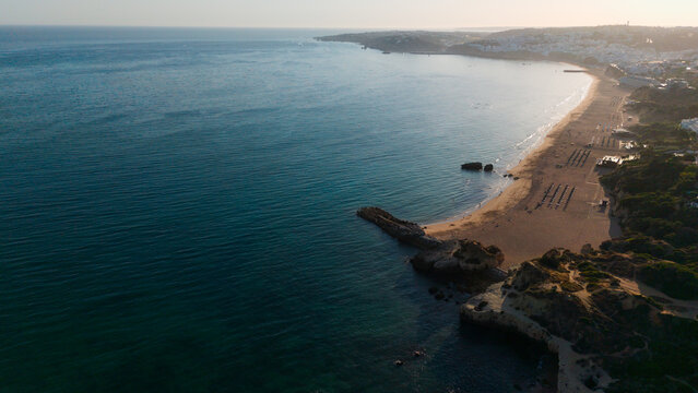 peaceful beach sunset over rocky shore with sandy beach and ocean water from aerial view. travel and vacation destination with serene landscape and natural beauty.